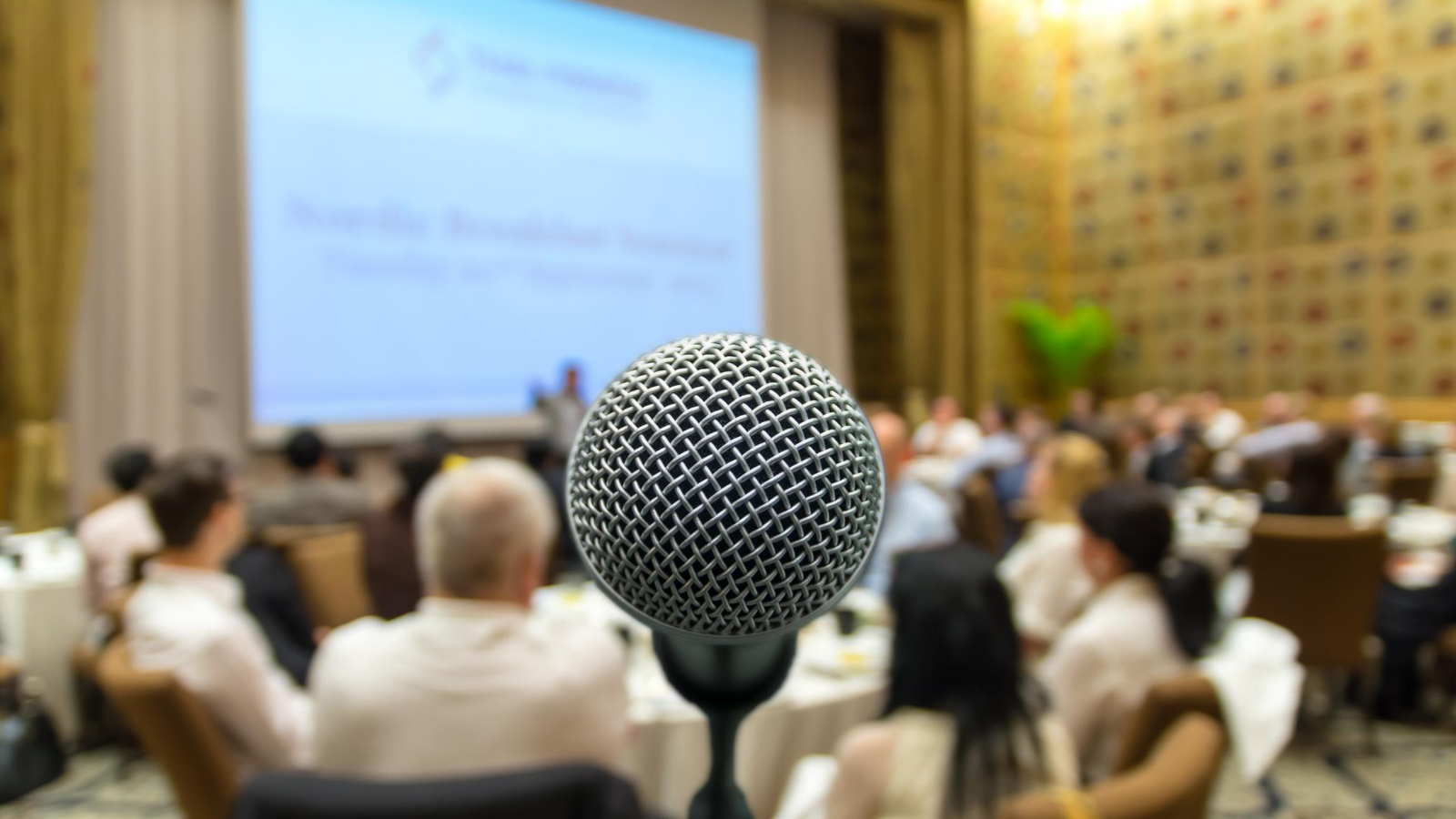 microphone standing in front of a large crowd of people