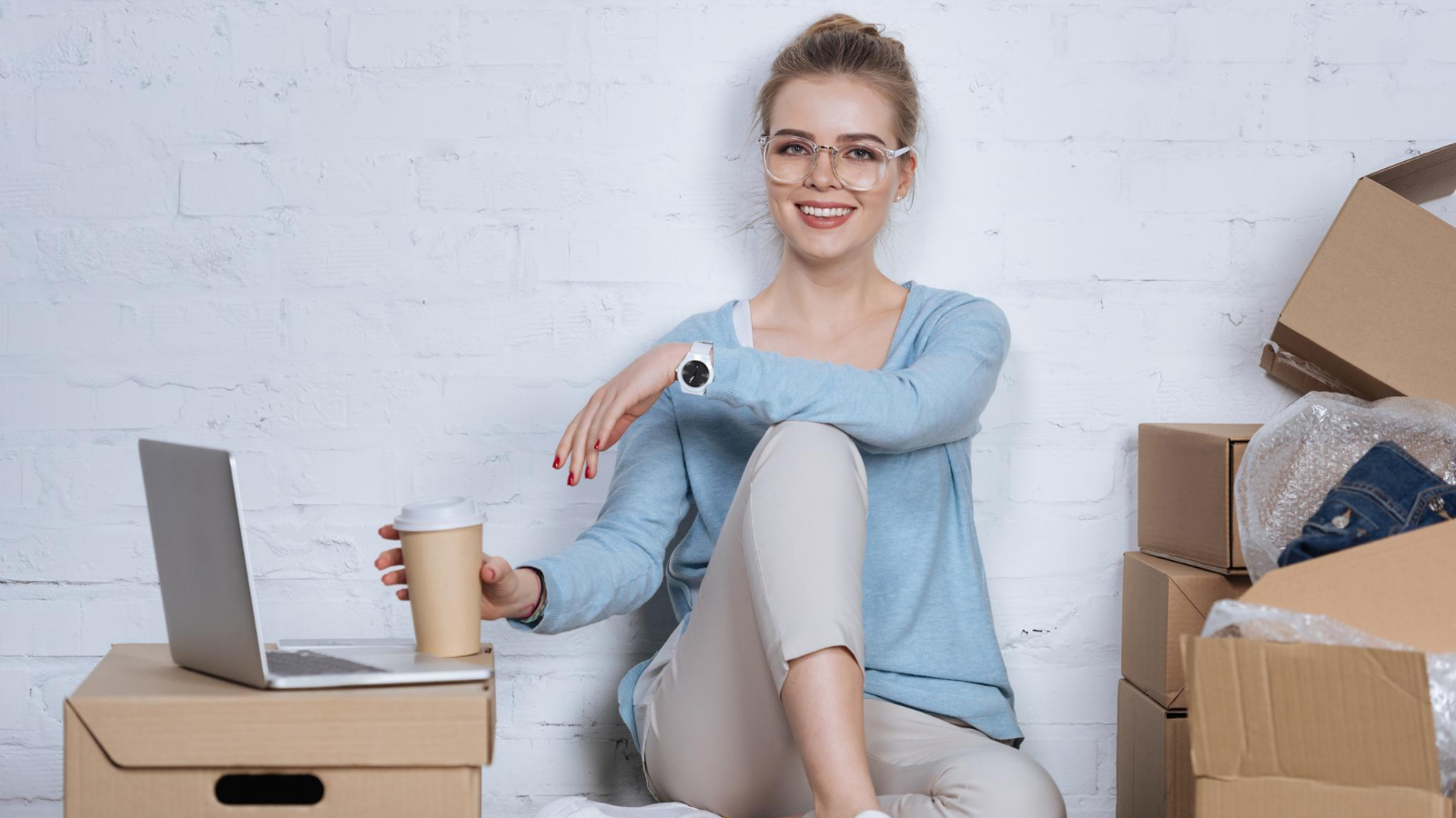 woman works at her laptop, surrounded by the products she is selling online