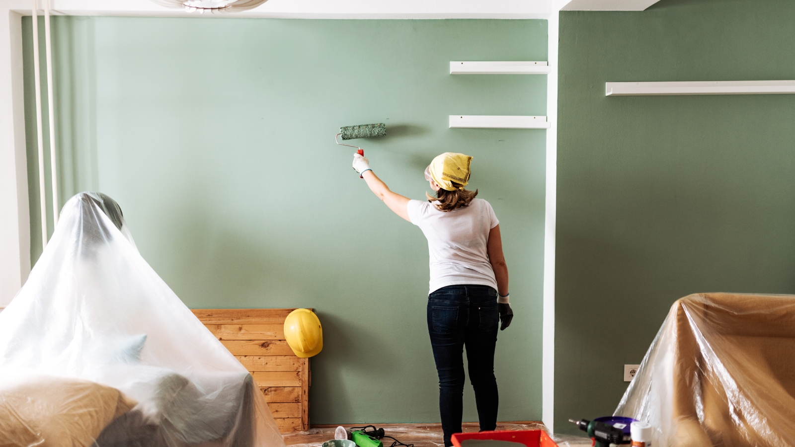 female painting the wall in a living room